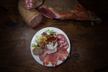mixed dish of typical Tuscan cold cuts including salami, raw ham, finocchiona lard, with toasted liver paté crostino, artichoke in oil, pickled onion  and dried cherry tomatoes from an old tavern
