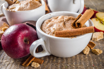 Quick autumn dessert idea. Autumn apple pie mugcake with red apples, cinnamon, spices, Rustic wooden background copy space