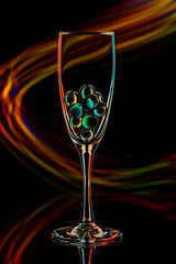 glass balls in a wine glass on a black background with colored light rays