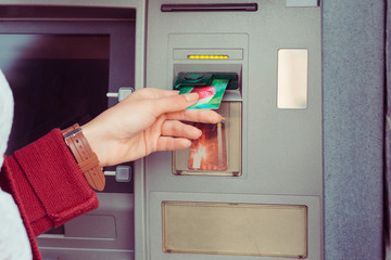 Hand of woman uses credit card to withdraw at Atm Bank terminal. Modern style. ATM cash terminal with display