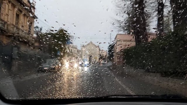Driving in the rain view from inside car with rain drops on car windshield. Rain drops on window car windshield
 Drops of water fall on the glass, making it difficult to view.