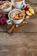 Quick autumn dessert idea. Autumn apple pie mugcake with red apples, cinnamon, spices, Rustic wooden background copy space