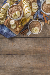 Portioned Banana bread mugcake in small mugs. Easy sweet baking idea, With fresh bananas, nuts, honey and spices on rustic wooden background copy space