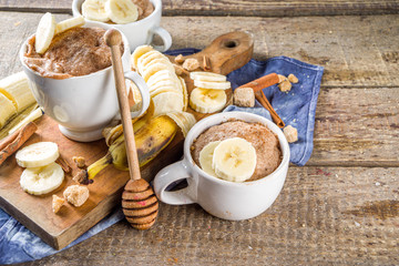 Portioned Banana bread mugcake in small mugs. Easy sweet baking idea, With fresh bananas, nuts, honey and spices on rustic wooden background copy space