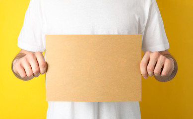 Man holds empty carton sheet on yellow background. Space for text