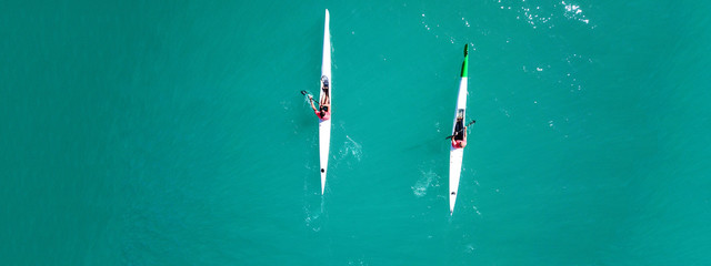 Aerial drone ultra wide top down photo of fit athletes competing in sport canoe in emerald lake