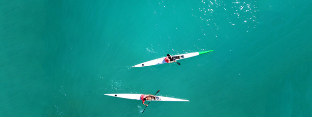 Aerial drone ultra wide top down photo of fit athletes competing in sport canoe in emerald lake