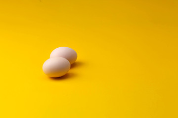two home-grown organic chicken eggs on a yellow background