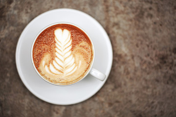 Cup of cappuccino with perfect latte art on the table. Top view, macro.