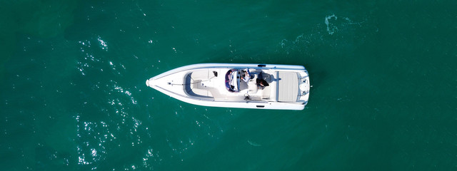 Aerial drone top down ultra wide photo of white speedboat cruise in low speed in emerald clear...