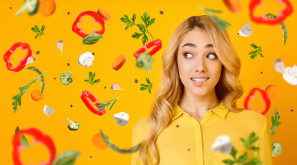 Obraz na płótnie Canvas Healthy eating habits. Charming blonde lady on orange background, collage with vegetables flying in air