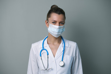 A female doctor in a white robe and mask with a stethoscope.