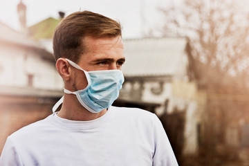 A young man in a medical mask walking along an empty street due to quarantine due to an outbreak of coronavirus in the world. The fight against coronavirus. Masked guy on empty street background close