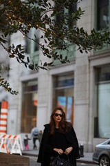 Obraz premium A beautiful woman in a black long coat walks through the streets of New York