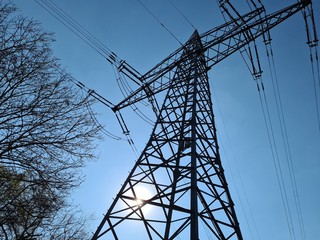 sonne strahlt durch einen strommast 
