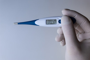 Obraz premium Hand in a medical glove holds a thermometer.