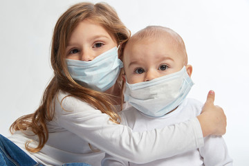 A brother and sister wearing white shirts and face masks on a white background