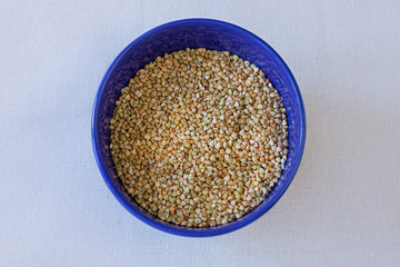 Green buckwheat in blue porcelain bowl, natural shadow.Dry unroasted whole grain superfood flat lay.Organic healthy food, weight loss, reduce inflammation,help manage diabetes,maintaining heart health