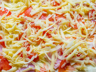 Preparation for baking in the form of tomatoes and ham laid out on the dough and sprinkled with grated cheese