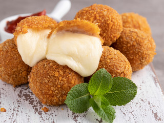 Roasted breaded mozzarella cheese balls with tomato sauce close up