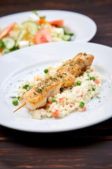 chicken kebab with rice and vegetables on the wooden background