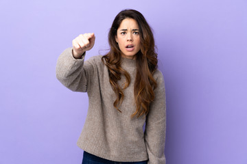 Woman over isolated purple background frustrated and pointing to the front