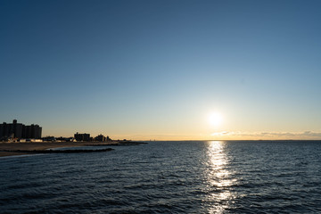 Fototapeta na wymiar Sunrise over Atlantic Ocean, blue sky, piers. Pier and blue Atlantic Ocean. Red sky sun beams. 