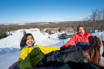 Girlfriends snow tubing in the winter in Canada