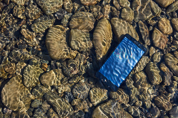 Accident. The Mobile phone fall to the river near the beach. Smartphone dropped, waterproof system or insurance concept.