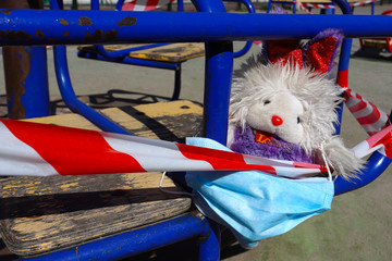 Rabbit teddy with protective mask, forgotten on the playground, wrapped with Covid-19 virus protective tape, concept of child and family health