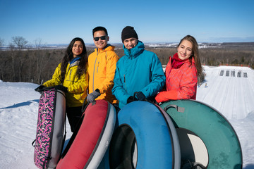 Group of multiracial millenials snow tubing in the winter in Canada