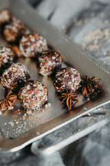 Homemade healthy vegan chocolate truffles with dates, coconut flakes and rolled oats served on silver tray
