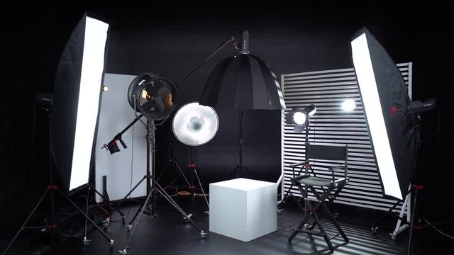 Dark room cyclorama. Modern photo studio with professional equipment. Empty photo studio with lighting equipment. Interior of modern photo studio with director production chair.