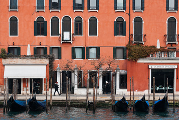 Fototapeta na wymiar Venice, Italy - February 19 2020 : View of Grand Canal with gondolas and beautiful red building 