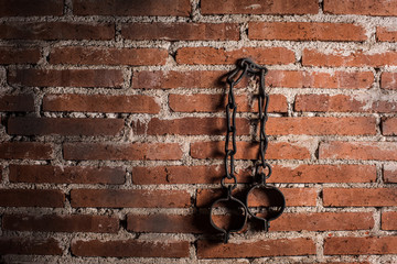 Slavery and bondage strong steel old shackles isolated on bricks background - obrazy, fototapety, plakaty
