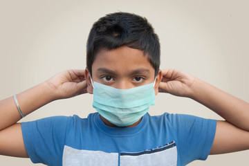 Corona virus outbreak: boy putting on a medical disposable mask to avoid contagious viruses
