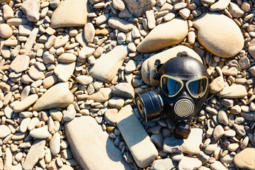 Post Apocalyptic background. Gas mask on the river rocks. Chemical respirator symbol of danger.