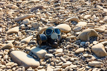 Post Apocalyptic background. Gas mask on the river rocks. Chemical respirator symbol of danger.