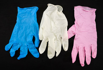 pink, white and blue gloves on a black background. Medical gloves.