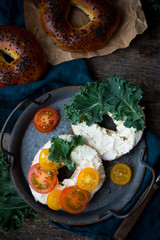 Homemade bagels with cheese and vegetables for brunch on an old wooden background