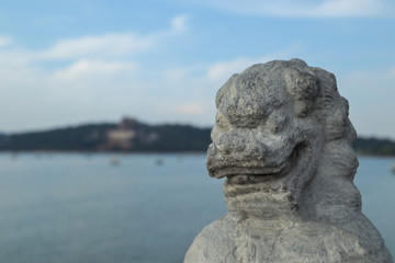Close up of a dragon's portrait statue with a lake in the background