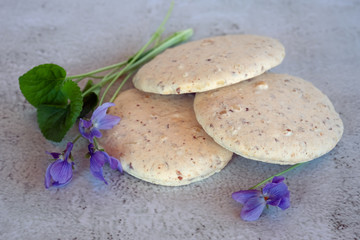 Nutty homemade cookies lying in a pile on the table with purple violets