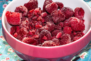 delicious frozen raspberries in extreme close-up in a red bowl