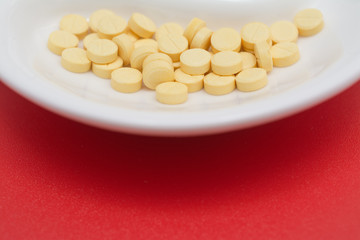 near portion of a plate with pills on a red background and place for your text, treatment of coronavirus and pneumonia
