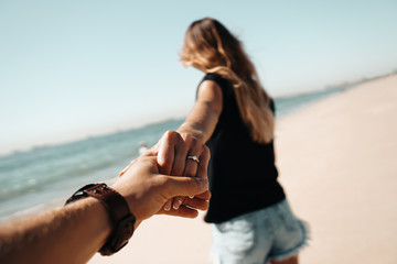 Fresh engaged couple enjoying a romantic engagement day on the beach during a sunny day. Close up...