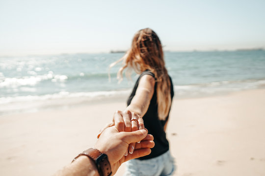 Fresh engaged couple enjoying a romantic engagement day on the beach during a sunny day. Close up on her ring.