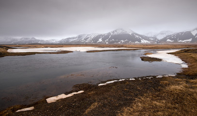 Icelandiclandscape with frozen lake and mountains covered in snow in Iceland