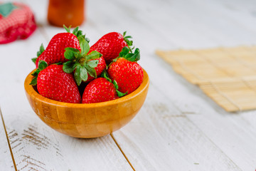 Organic strawberries on a cutting board fruit and a bowl on a white wooden table