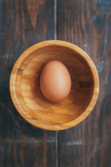 Organic eggs in a large wooden bowl on a wooden table