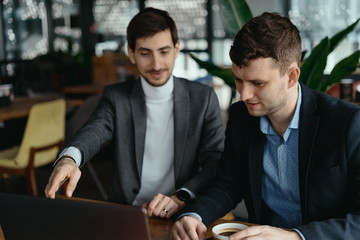 Two handsome businessmen are talking and pointing laptop screen while discussing. Business. Technology. Partnership.